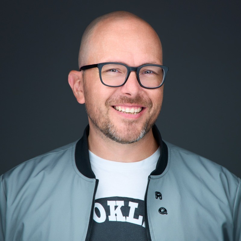 Doug Black, smiling, wearing glasses and a grey jacket